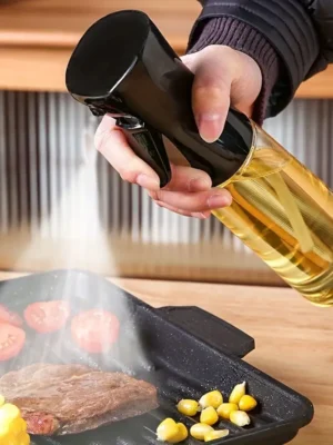 Hand spraying oil on a grilling pan with steak and vegetables for cooking.